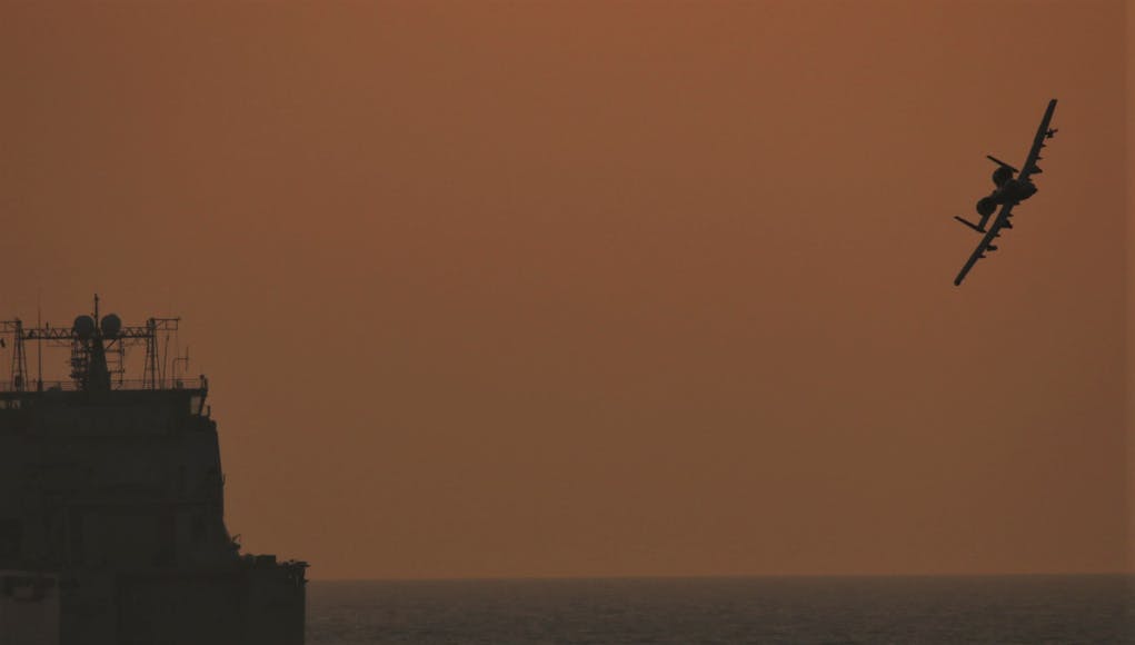 An A-10 banks off the bow of RFA Cardigan Bay
