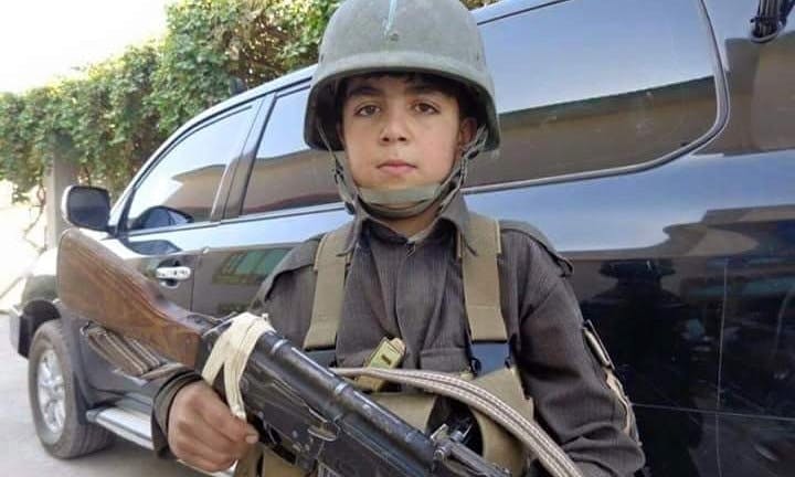 Child soldier Wasil Ahmad wearing a kevlar helmet and uniform